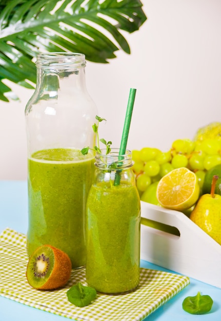 Fresh blended green smoothie in glass bottles with fruit and vegetables . Health and detox concept.