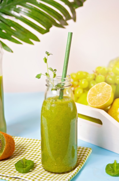 Fresh blended green smoothie in glass small bottle with fruit and vegetables . Health and detox concept.