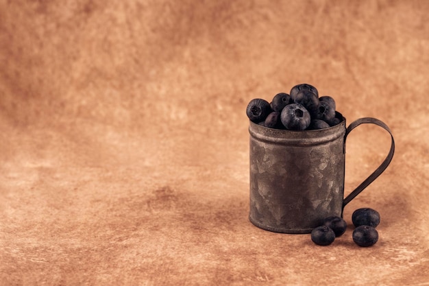 Fresh blueberries in a cup on brown background Copy space