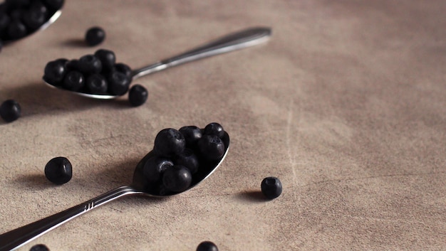 Fresh blueberries in a metal spoon on a gray background