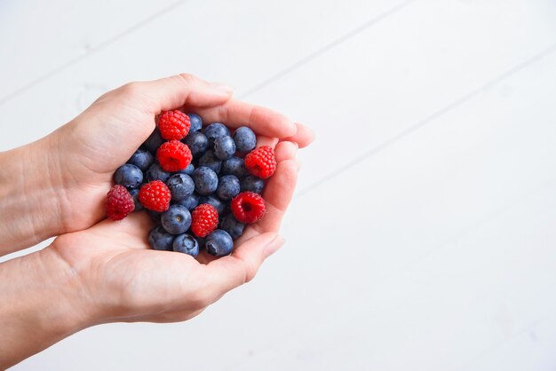 Photo fresh blueberries and raspberries in women's hands 