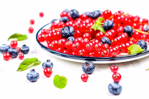 Fresh blueberries and red currants with mint leaves in a wooden bowl on burlap 