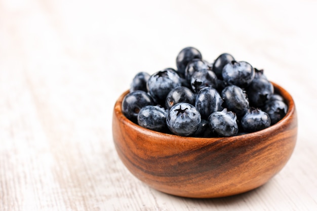 Fresh blueberries in a wooden bowl on white table