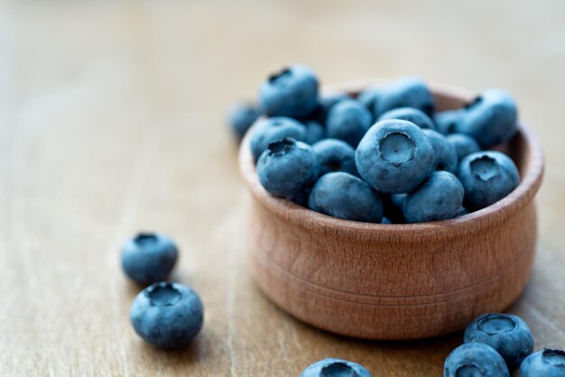 Fresh blueberries in a wooden bowl on wooden surface background Concept for healthy nutrition