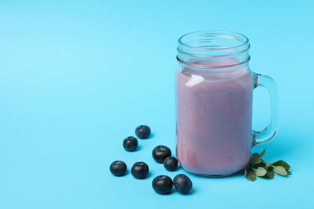 Fresh blueberry smoothie and ingredients on blue background