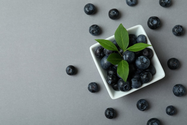 Fresh blueberry with leaves on gray surface