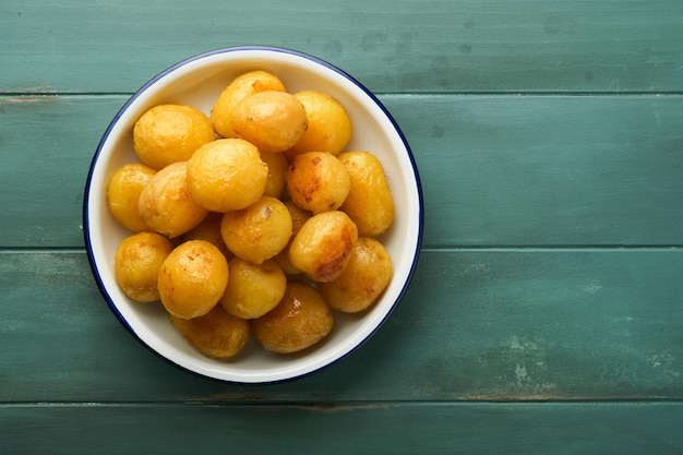 Fresh boiled new or young potatoes with butter fresh dill and onions in white bowl on old rustic wooden background Tasty new boiled potatoes Top view