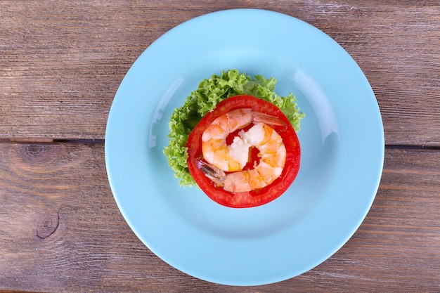 Fresh boiled prawns with pepper on a big blue round plate on wooden background