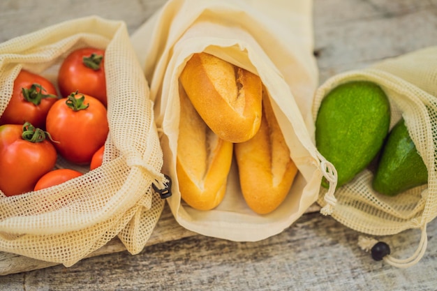 Fresh bread avocado and tomatoes in a reusable bag on a stylish wooden kitchen surface zero waste