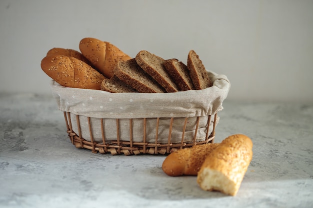 Fresh bread baguette with sesame seeds and slices of rye bread are in the breadbox on the table. Bakery. Flat lay. Close-up, minimalism.