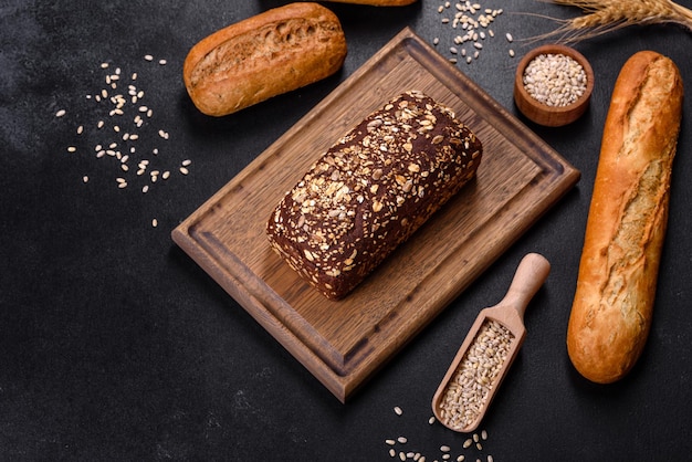 Fresh Bread on black background, top view, copy space. Homemade fresh baked various loafs of wheat and rye bread