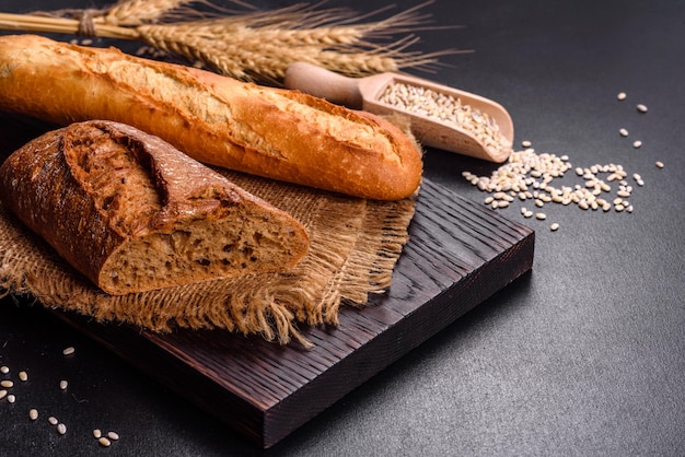 Fresh Bread on black background, top view, copy space. Homemade fresh baked various loafs of wheat and rye bread