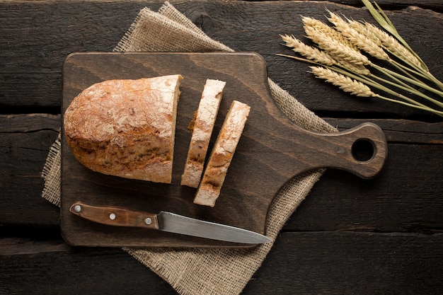 Fresh bread on a board with wheat on wood