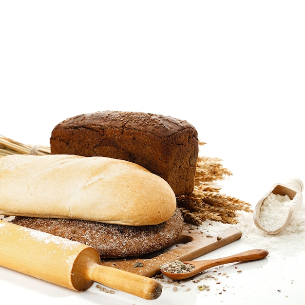 Fresh bread on cutting Board, scoop with flower and seeds isolated over white