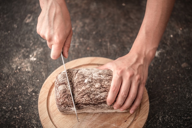 fresh bread in hands closeup on old wooden table