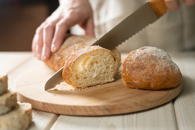 Fresh bread slice and cutting knife on rustic table