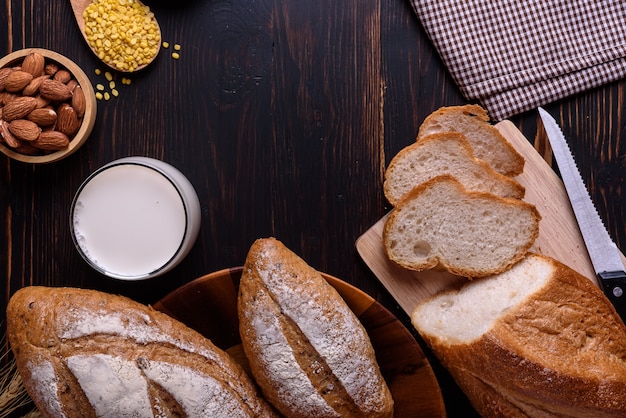 Fresh bread with milk on black wooden table.