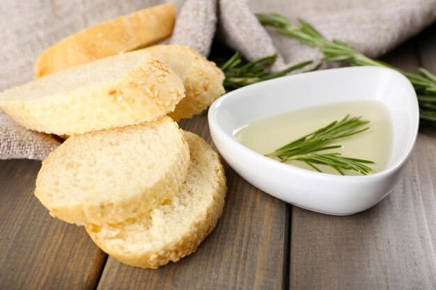 Fresh bread with olive oil and rosemary on wooden table