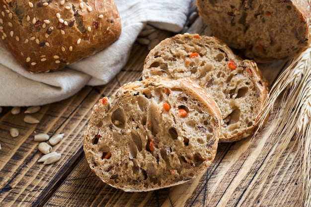 Fresh bread with sunflower seeds, sesame seeds and flax are cut into pieces on a cutting board.