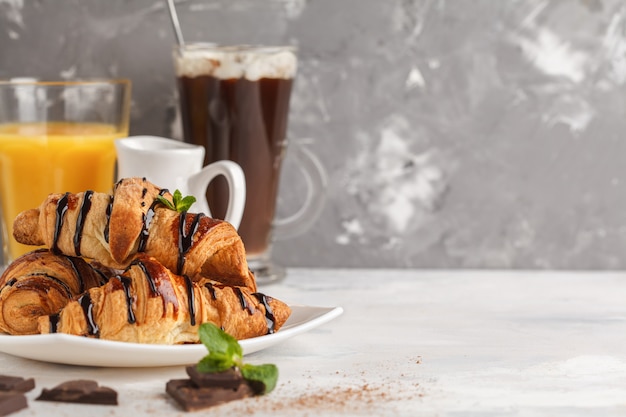 Fresh breakfast croissants with chocolate syrup, orange juice and cocoa with marshmelow. Copy space. French cuisine dessert concept.