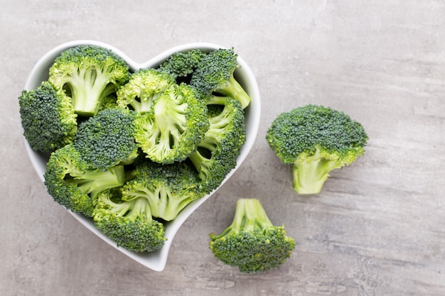 Fresh broccoli in a heart shaped bowl on a wooden table