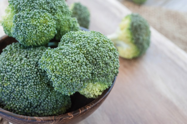 fresh broccoli in wooden bowl on wood table for background