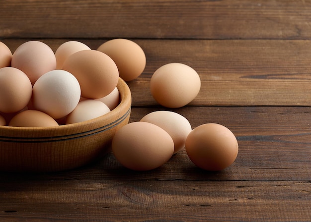 Fresh brown chicken eggs in a round wooden plate on the table