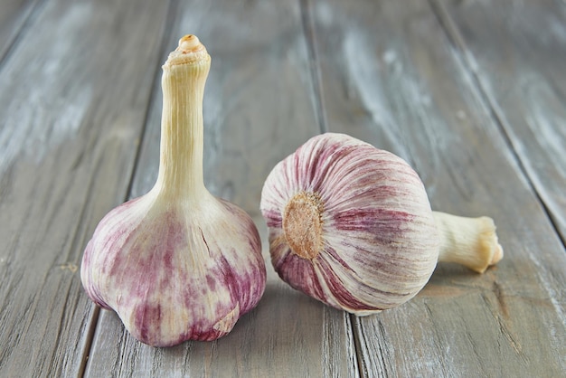 Fresh bulbs of garlic stacked on wooden gray background