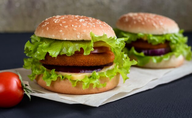 fresh burger with cheese, cutlet and tomato on the black background