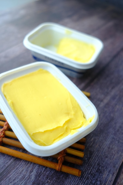 Fresh butter in a container with bread on white background