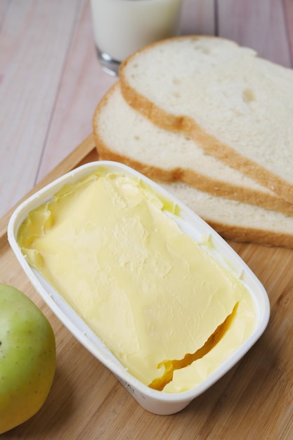 Fresh butter in a container with bread on white background