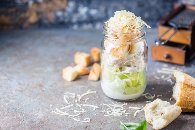 Fresh caesar salad in a glass jar with ingredients