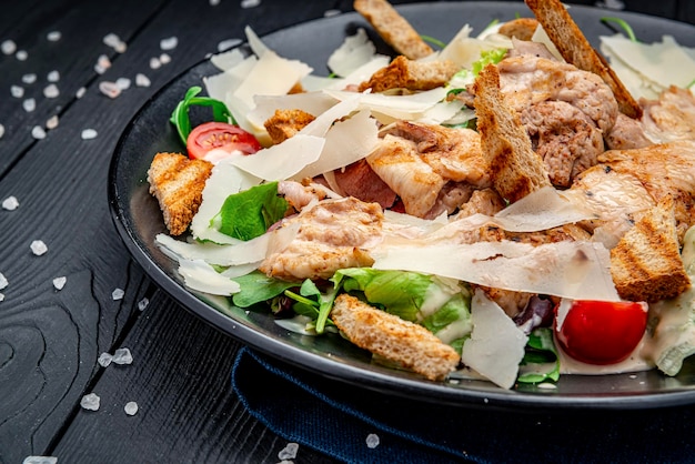 Fresh caesar salad in white plate on dark wooden table Top view