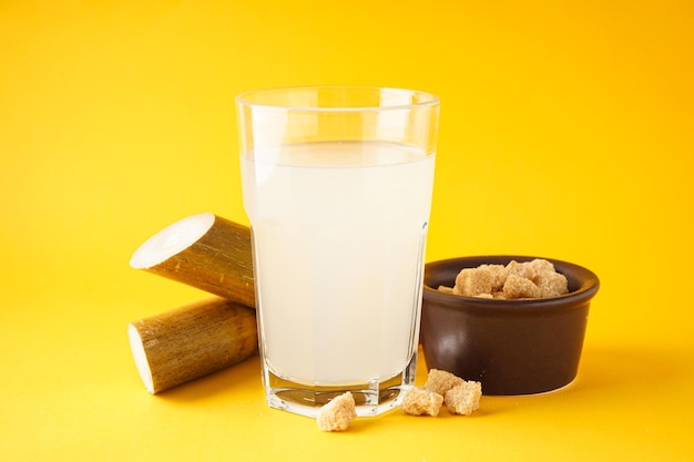 Fresh cane juice and granulated brown sugar on a colour background closeup