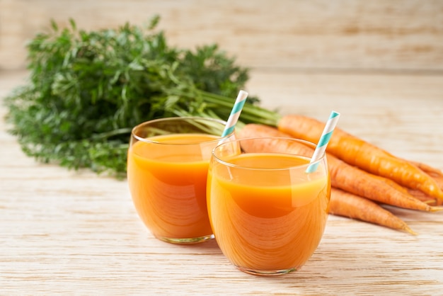 Fresh carrot juice in glasses on a  white wooden table, selective focus. Healthy detox diet.