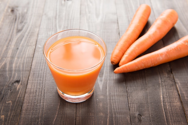 Fresh carrot juice on wooden background