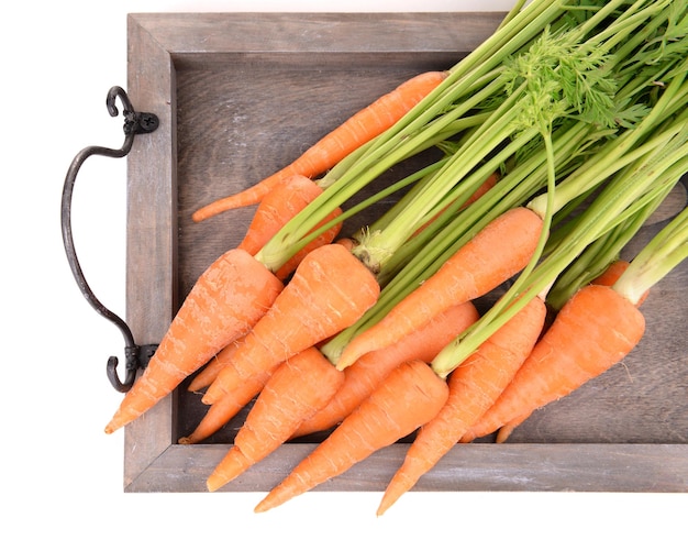 Fresh carrot on wooden tray close up