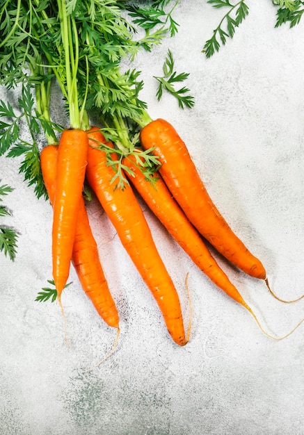 Fresh carrots bunch on grey stone background Top view frame with copy space