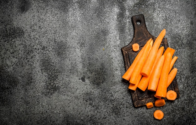 Fresh carrots on the old Board. On rustic table.