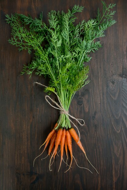 Fresh carrots on an old wooden board. Young carrots. Healthy food balance. Table background menu. Space for text.