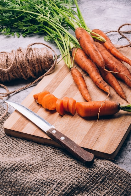 Fresh carrots sliced with a knife on a cutting board