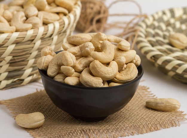 Fresh cashewnut served in a bowl isolated on napkin side view of nuts on grey background