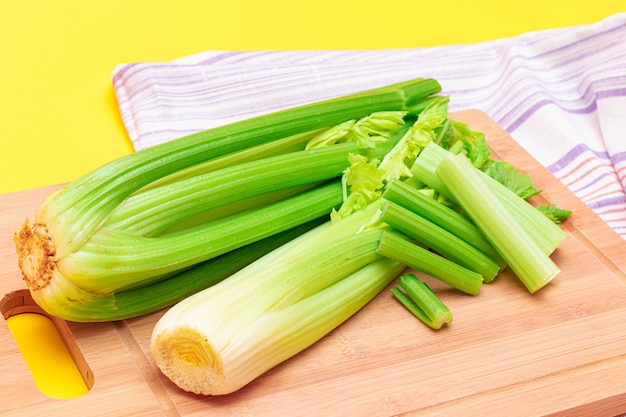 Fresh celery stem and chopped celery sticks on wooden cutting board