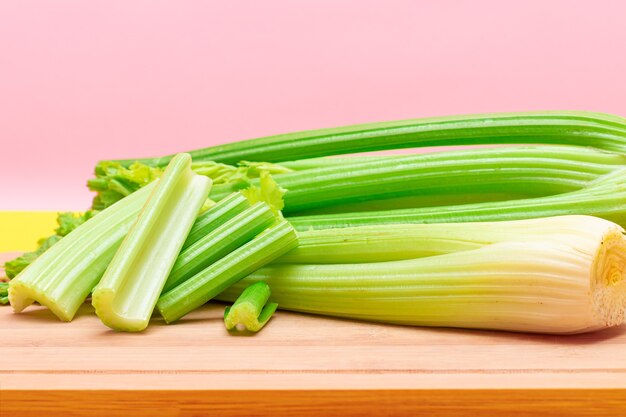 Fresh celery stem and chopped celery sticks on wooden cutting board