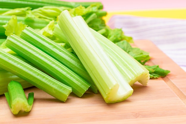 Fresh celery stem and chopped celery sticks on wooden cutting board