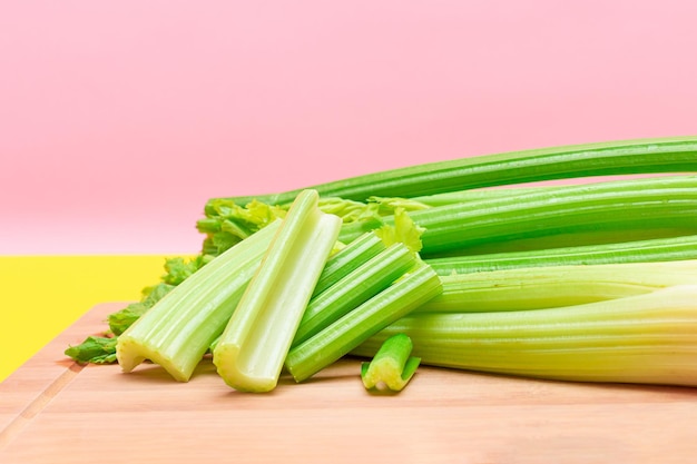 Fresh celery stem and chopped celery sticks on wooden cutting board