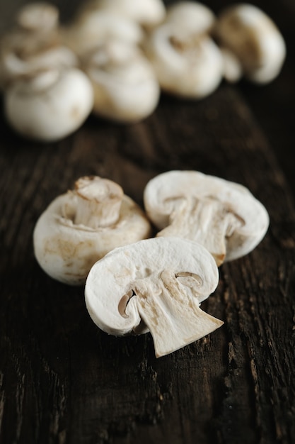 Fresh champignon mushrooms on wooden table, closeup.