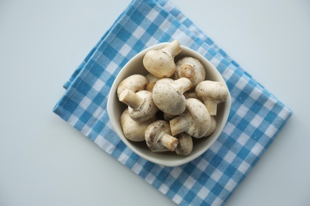 Fresh champignons mushroom in a white bowl on table