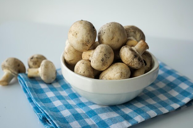 Fresh champignons mushroom in a white bowl on table