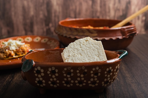 Fresh cheese in clay pot on wood table